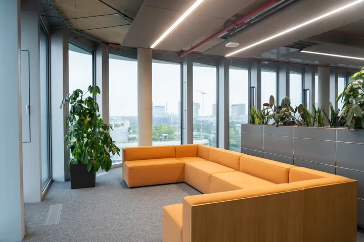 Lounge mit orangefarbenem Sofa und Fensterfront in der 7. Etage