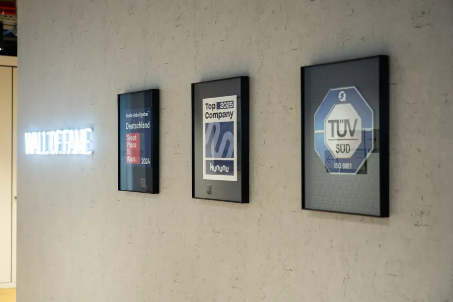 Wall of Fame mit Auszeichnungen: Great Place to Work, kununu Top Company, TÜV SÜD ISO 9001
